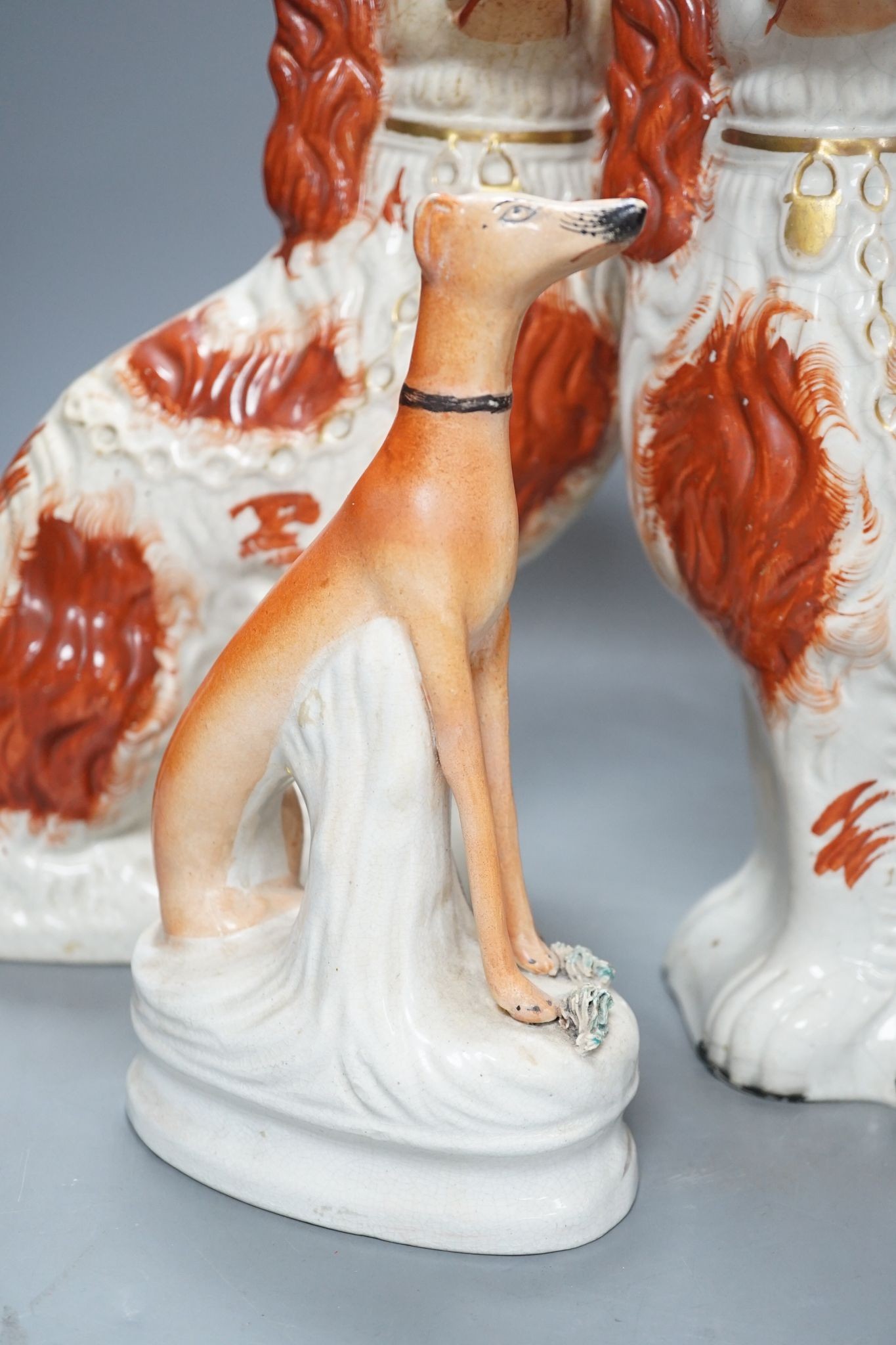 A pair of Victorian Staffordshire Spaniel chimney dogs and a greyhound, chimney dogs 31 cms high.